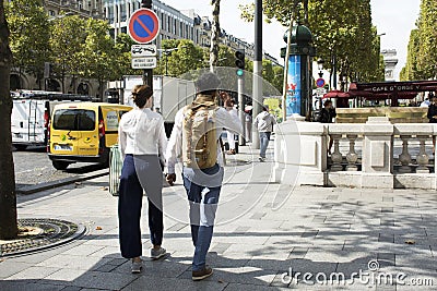 French people boyfriend and girlfriend walking hand in hand on walkway at sidewalk in Lâ€™avenue des Champs-Elysees Editorial Stock Photo